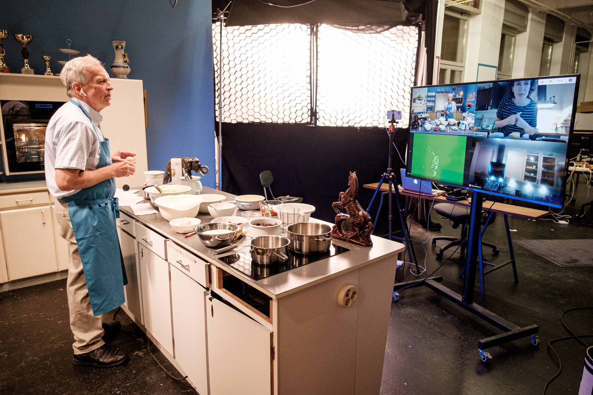 Opa Johannes steht im Backademie Studio beim Live Backkurs und redet mit Personen über einen Bildschirm