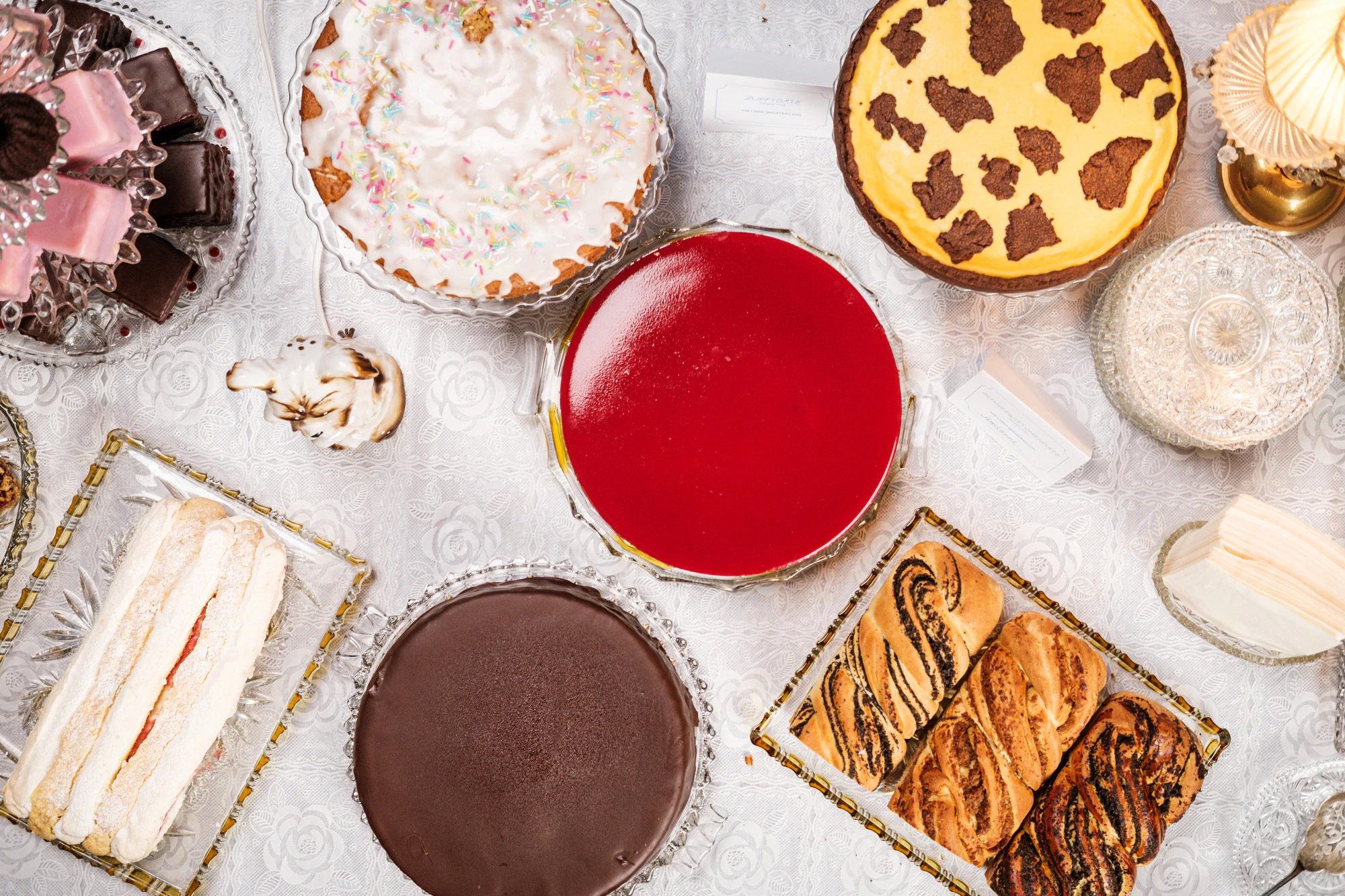 Kuchenbuffet der Vollpension mit Vitrinen-Rückwand, Vintage-Lampen und Torten auf Bleikristall-Tellern